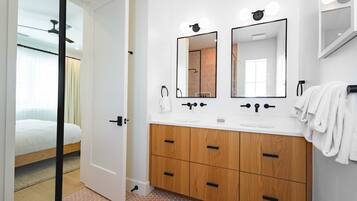 A modern bathroom with a double sink, wooden cabinets, and a large mirror.