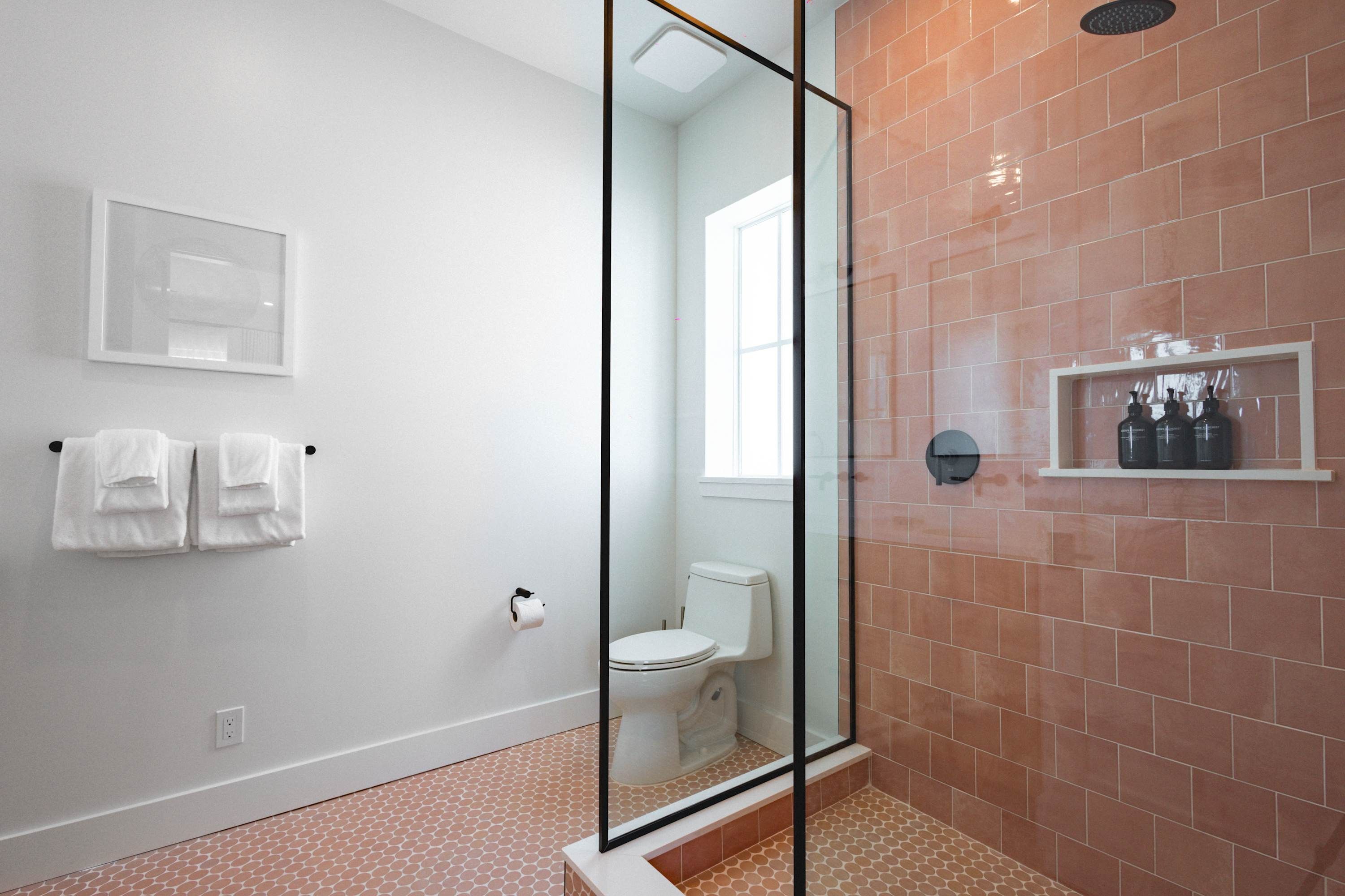 A bathroom with a glass-enclosed shower, a toilet, and a white sink.