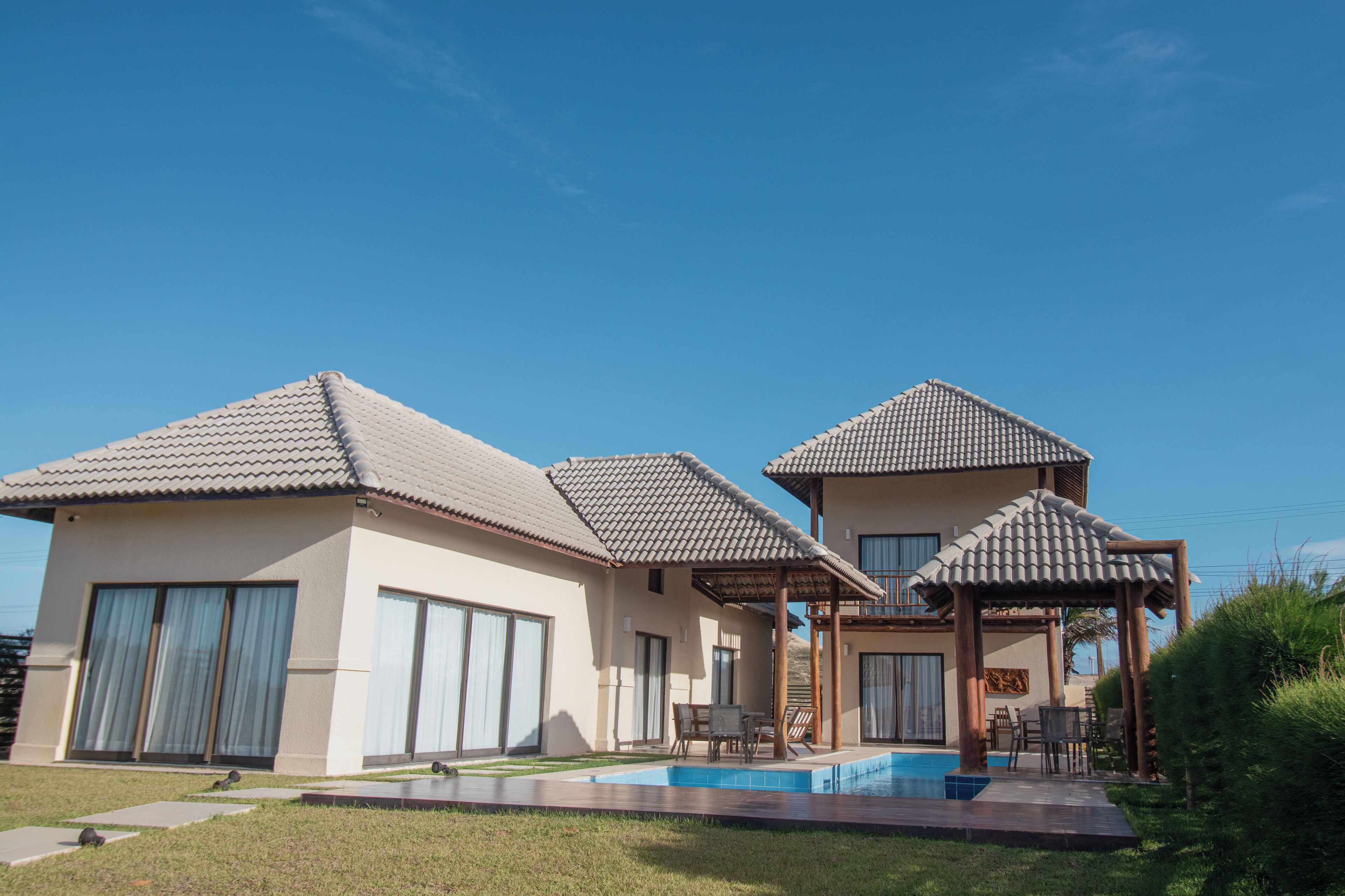 A modern two-story house with a swimming pool, large windows, and a patio area.