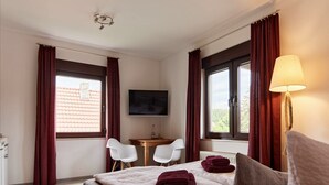 Een hotelkamer met een bed, twee stoelen, een televisie en een lamp.