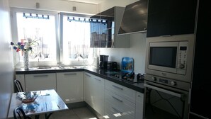 A modern kitchen with white cabinets, a black countertop, a stove, and a microwave.