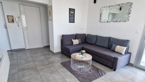 A modern living room with a grey sofa, a round coffee table, and a chandelier.