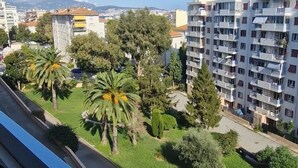 A residential area with multi-story apartment buildings, green spaces, and a clear blue sky.