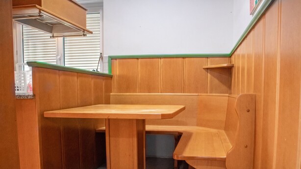 Una cocina compacta con armarios de madera, un banco integrado y una pequeña encimera.