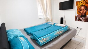 Un dormitorio con una cama, un televisor y un cartel en la pared.