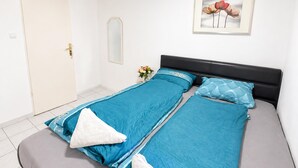 Una habitación con dos camas individuales, una puerta, un espejo y un cuadro en la pared.