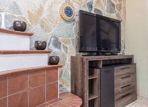 A stone wall with a flat-screen TV mounted on a wooden entertainment unit.