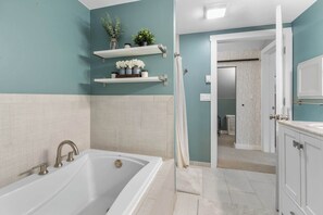 Ein Badezimmer mit Badewanne, weißen Fliesen und einer Duschvorhang.