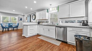 A modern kitchen with white cabinets, stainless steel appliances, and a wooden floor. - Sleeps 8 - Central Golf Getaway (Atlanta)