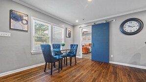 A dining area with a glass table and blue upholstered chairs, a clock on the wall, and a blue door leading to another room. - Sleeps 8 - Central Golf Getaway (Atlanta)