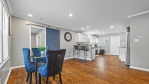 A spacious living area with a dining table and chairs, a kitchen in the background, and a large window providing natural light. - Sleeps 8 - Central Golf Getaway (Atlanta)