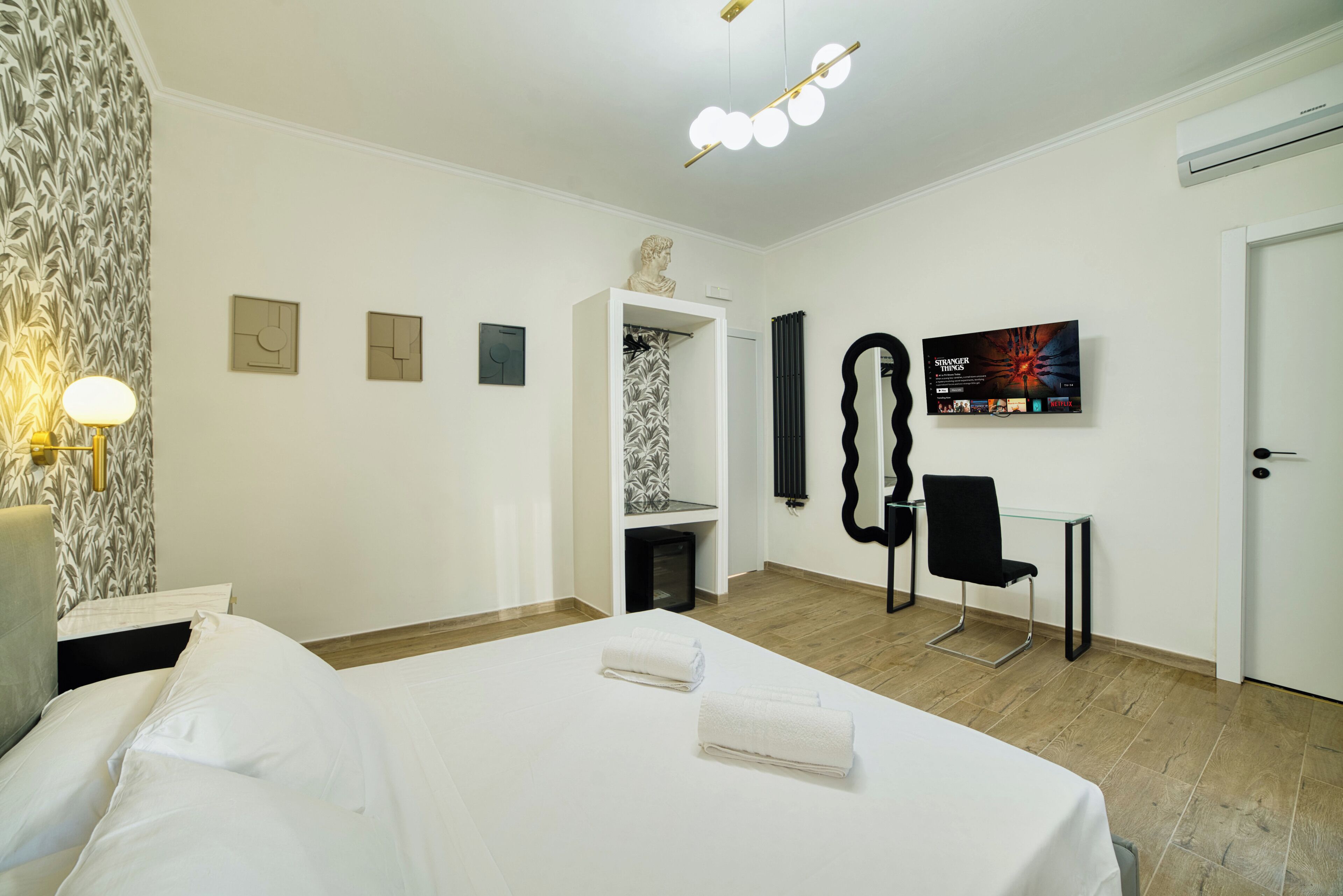 Ein Hotelzimmer mit Bett, Schreibtisch, Stuhl, Fernseher und Kleiderschrank.