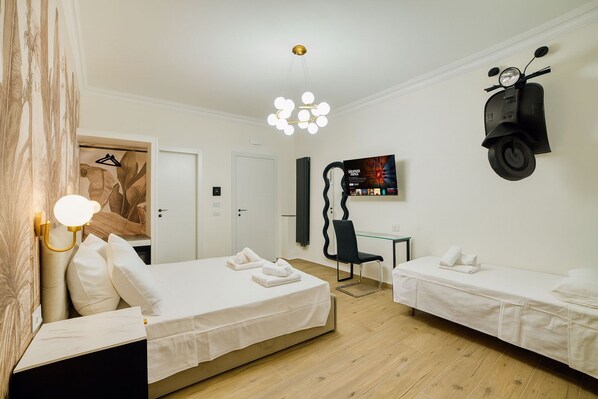 A modern hotel room with two single beds, a desk, a chair, a TV, and a scooter. - Radio Suites (Rome)