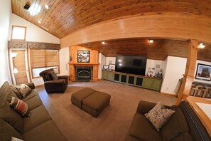 Una sala de estar acogedora con chimenea, techo de madera y televisor.