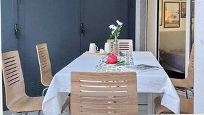 A dining table set with a white tablecloth, wooden chairs, a vase with flowers, and a small table with a teapot and cups. - Annasole's flat by Domus&Dimore (Rome)