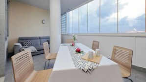 A modern dining area with a long table, wooden chairs, and a view of the sky through large windows. - Annasole's flat by Domus&Dimore (Rome)