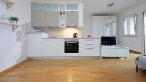 A modern kitchen with white cabinets, a built-in oven, and a dining area with a white table and chairs. - Annasole's flat by Domus&Dimore (Rome)