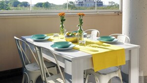 A dining table with a yellow tablecloth, blue plates, and two vases with orange flowers.