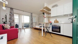 Une cuisine moderne avec des meubles blancs, un four encastré et un coin repas comprenant une table et des chaises.