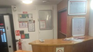 A reception desk with a no-smoking sign, a fire extinguisher, and a bulletin board with notices. - Enzo Hotels 1er Prix Dreux (Dreux)