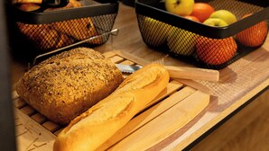 A breakfast buffet with bread, fruits, and a water dispenser. - Enzo Hotels 1er Prix Dreux (Dreux)