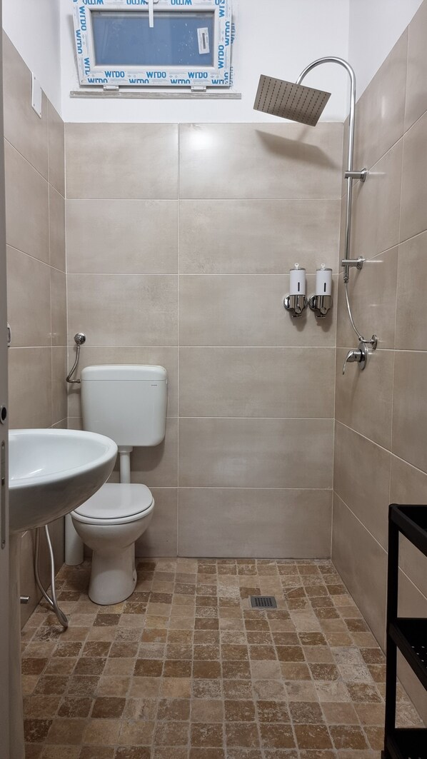 A small bathroom with a toilet, sink, and shower.