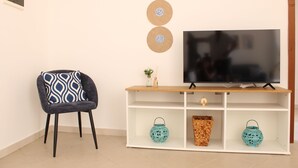 A living room with a TV on a white stand, a patterned armchair, and decorative wall art. - La Casa di Annamaria by Domus&Dimore (Pulsano)