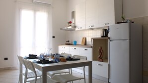 A kitchen with white cabinets, a white refrigerator, and a dining table with chairs. - La Casa di Annamaria by Domus&Dimore (Pulsano)