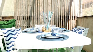 A round dining table set for four with white and blue tableware, surrounded by white chairs with blue and white patterned cushions. - La Casa di Annamaria by Domus&Dimore (Pulsano)