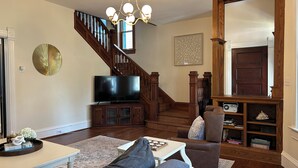 A living room with a TV, sofa, coffee table, and a staircase.