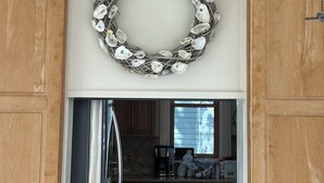 A kitchen with wooden cabinets, a stainless steel refrigerator, and a decorative wreath on the wall.