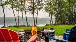 Un pozo de fuego junto al lago, con sillas y un letrero que dice "S'MORE Station".