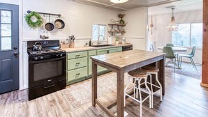 A kitchen with a wooden table, green cabinets, and a stove. - Yosemite Boho Bungalow, Pet Friendly + Mtn Views! (Coarsegold)