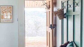 A hallway with a bench, a framed picture, and a door leading outside. - Yosemite Boho Bungalow, Pet Friendly + Mtn Views! (Coarsegold)