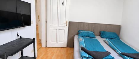 A room with a bed, a TV mounted on the wall, and a door with the number 4.
