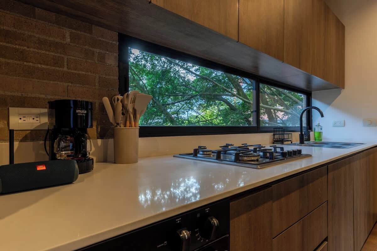 A modern kitchen with a large window, a coffee maker, and a set of utensils.