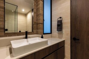 Un baño moderno con un lavamanos rectangular grande, un espejo y un perchero para toallas.