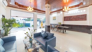 A spacious lobby with a wooden ceiling, a dining area, and a large window offering a view of the outdoors. - Peaceful 2 Hotel (Vientiane)