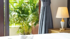A neatly made bed with towels, a lamp, and a potted plant in the background. - Peaceful 2 Hotel (Vientiane)