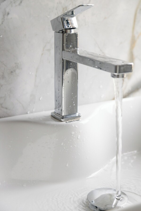 A modern bathroom with a chrome faucet and clear running water.