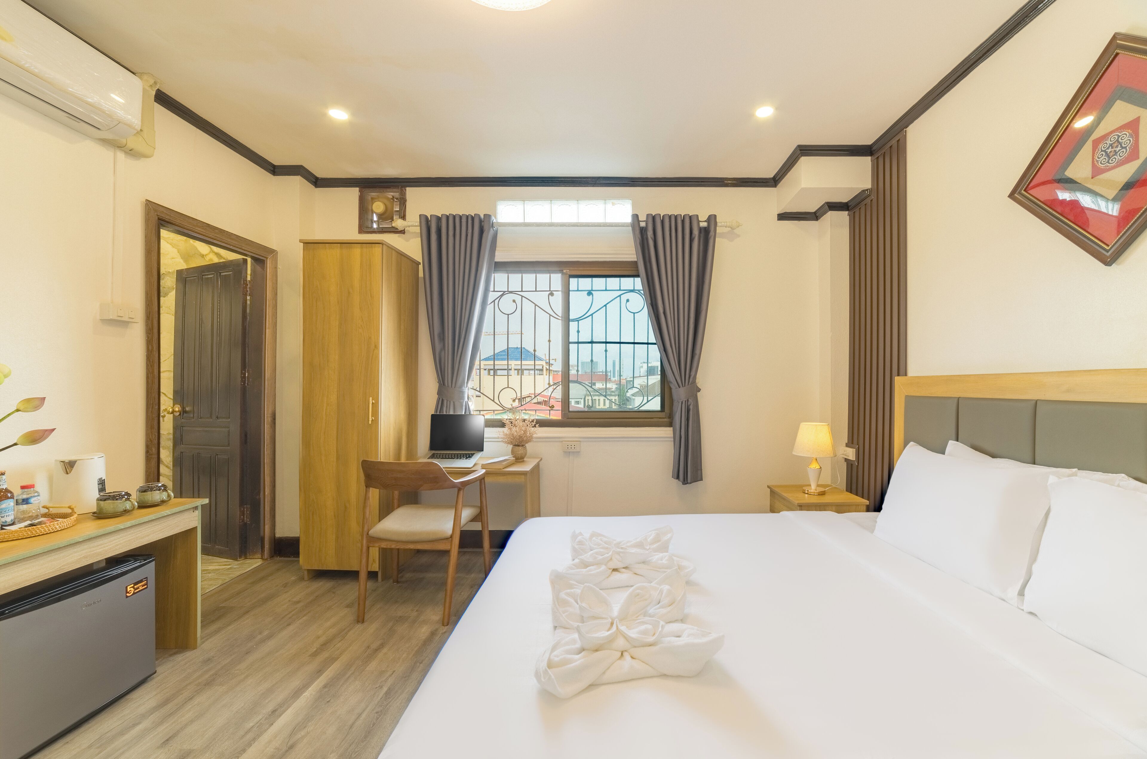 A hotel room with a bed, desk, chair, and a window with curtains.