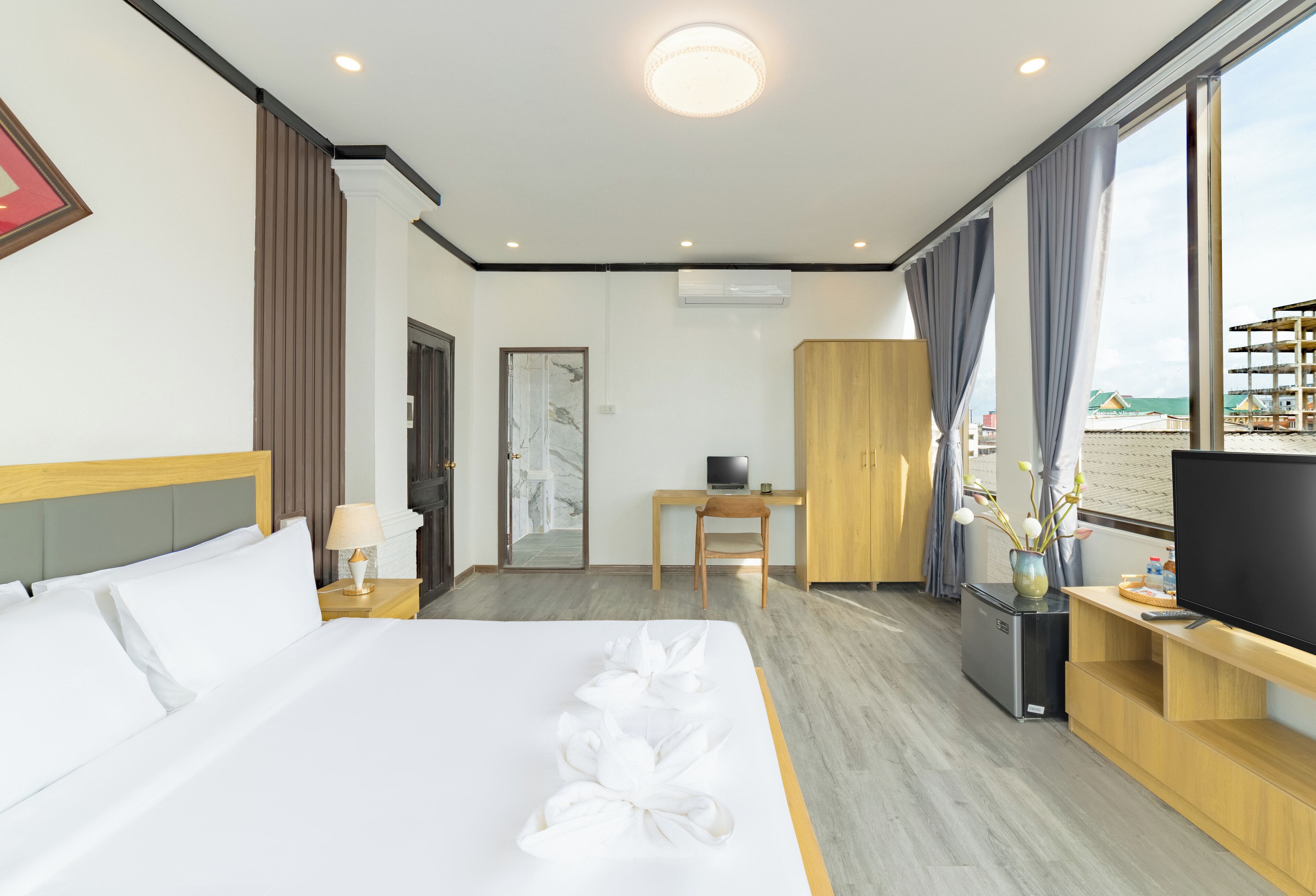 Ein Hotelzimmer mit Bett, Schreibtisch, Fernseher und Blick auf den Strand.