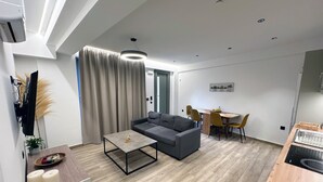 Ett modernt vardagsrum med en grå soffa, ett soffbord och en matplats med ett träbord och stolar.