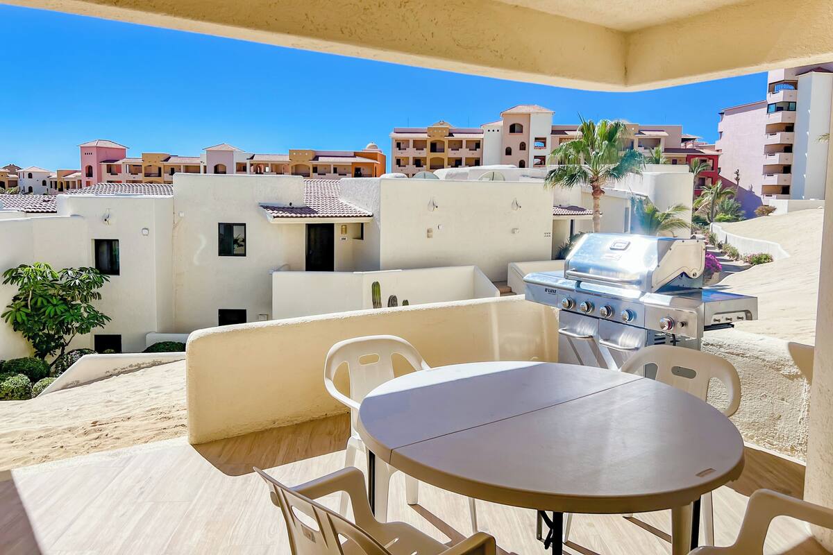 Ein Balkon mit Tisch, Stühlen, einem Grill und Blick auf die umliegenden Gebäude.