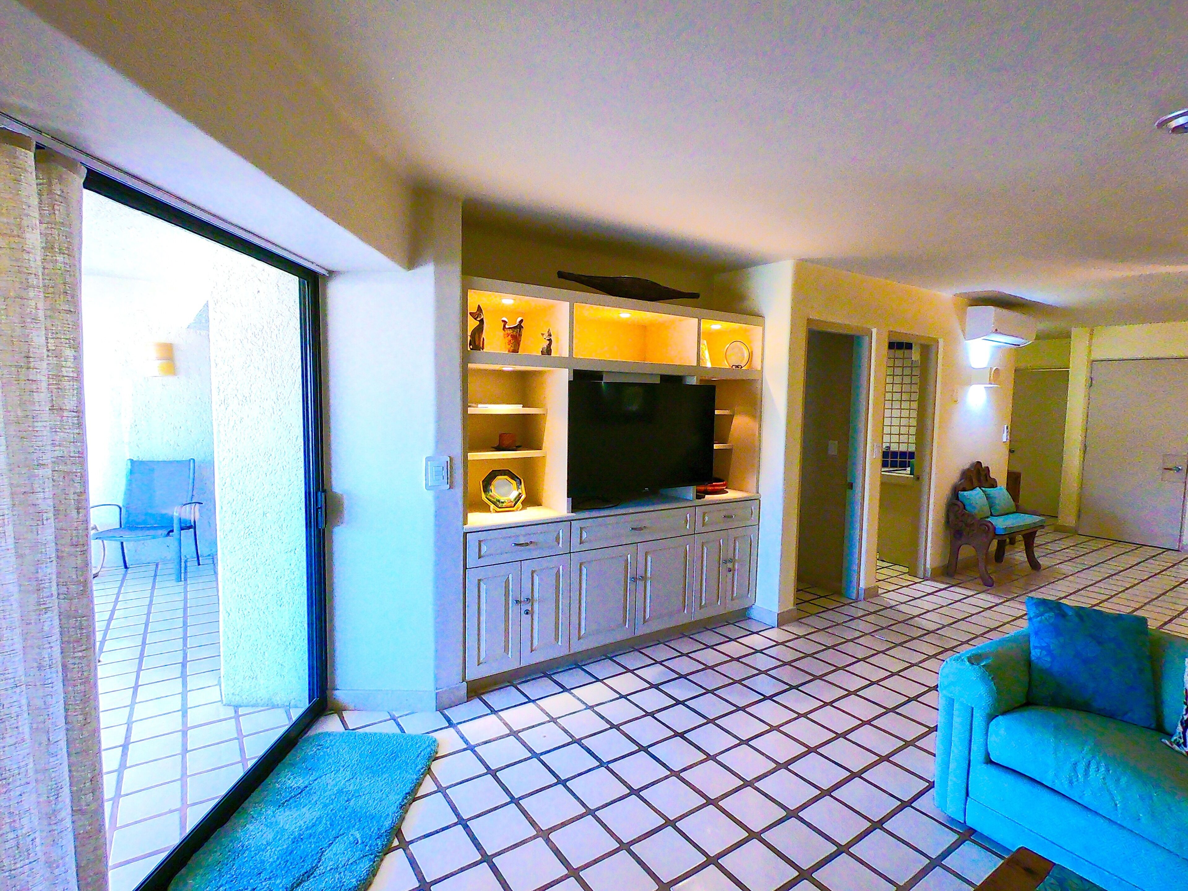 Una sala de estar con televisión, armarios y un sofá.