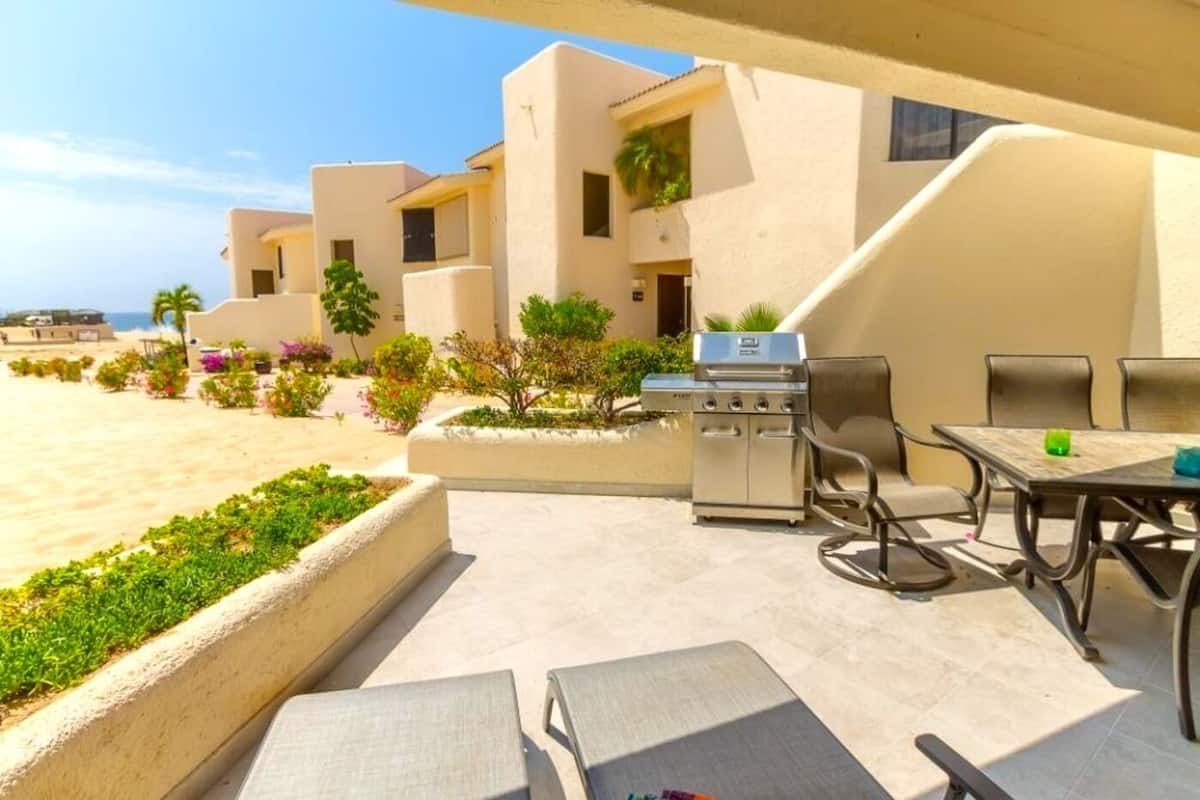 Eine Terrasse mit Grill, Sitzgelegenheiten im Freien und Blick auf den Strand.