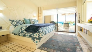 A bedroom with a bed, a nightstand, a bedside table, a patterned rug, and a view of an outdoor patio with a table and chairs. - Terrasol Oceanview Condo with Patio (Cabo San Lucas)