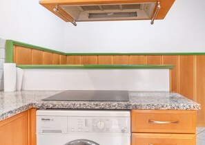 A kitchen with a built-in stove, a washing machine, and a wooden countertop. - Beautiful Room in Shared Villa | Garden & Parking (Wien)