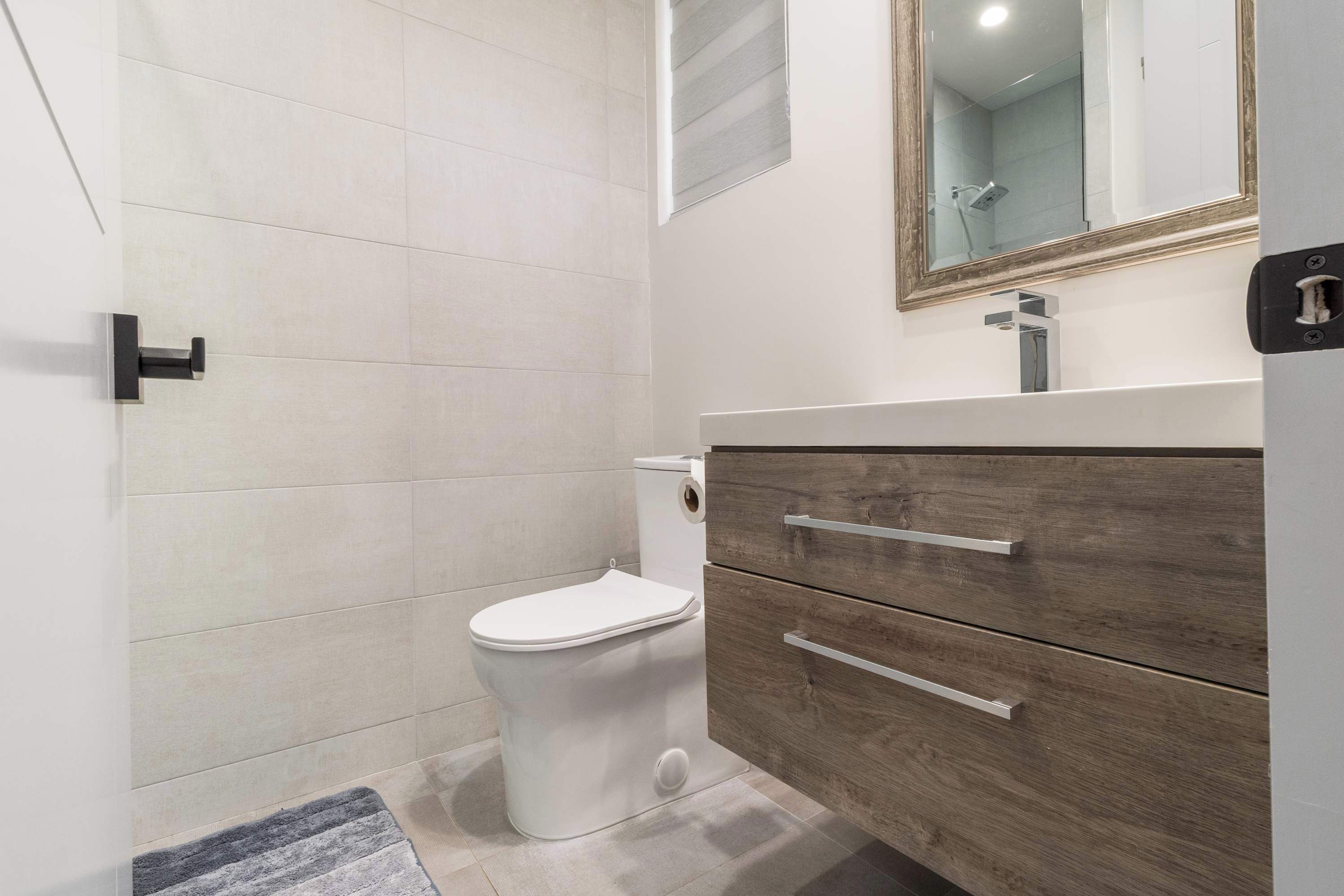 Ein modernes Badezimmer mit Toilette, Waschtisch und Spiegel.