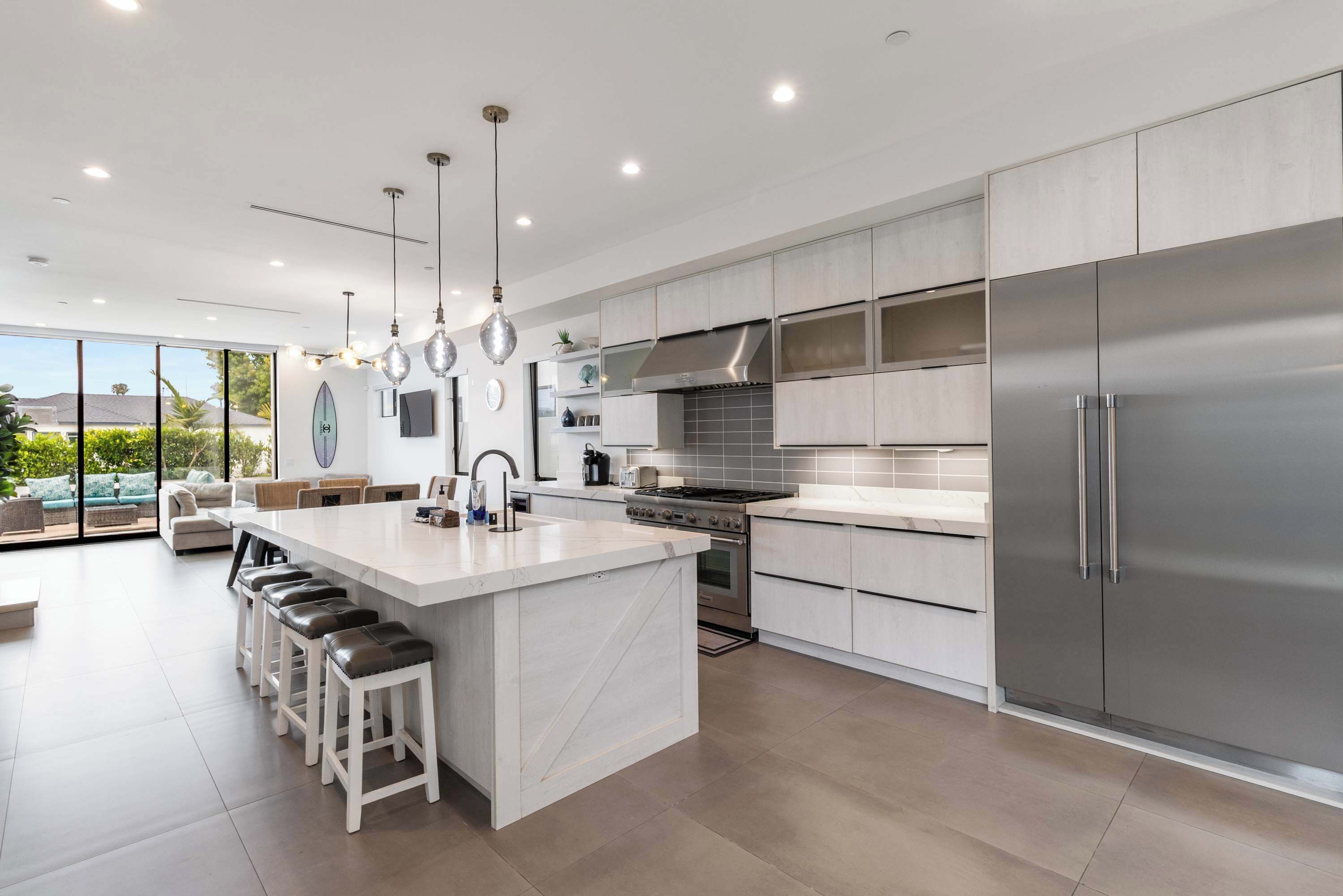 A modern kitchen with a large island, stainless steel appliances, and a view to the outdoors.